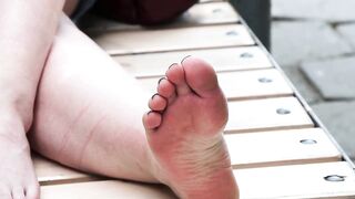 Women's dirty feet on a park bench.